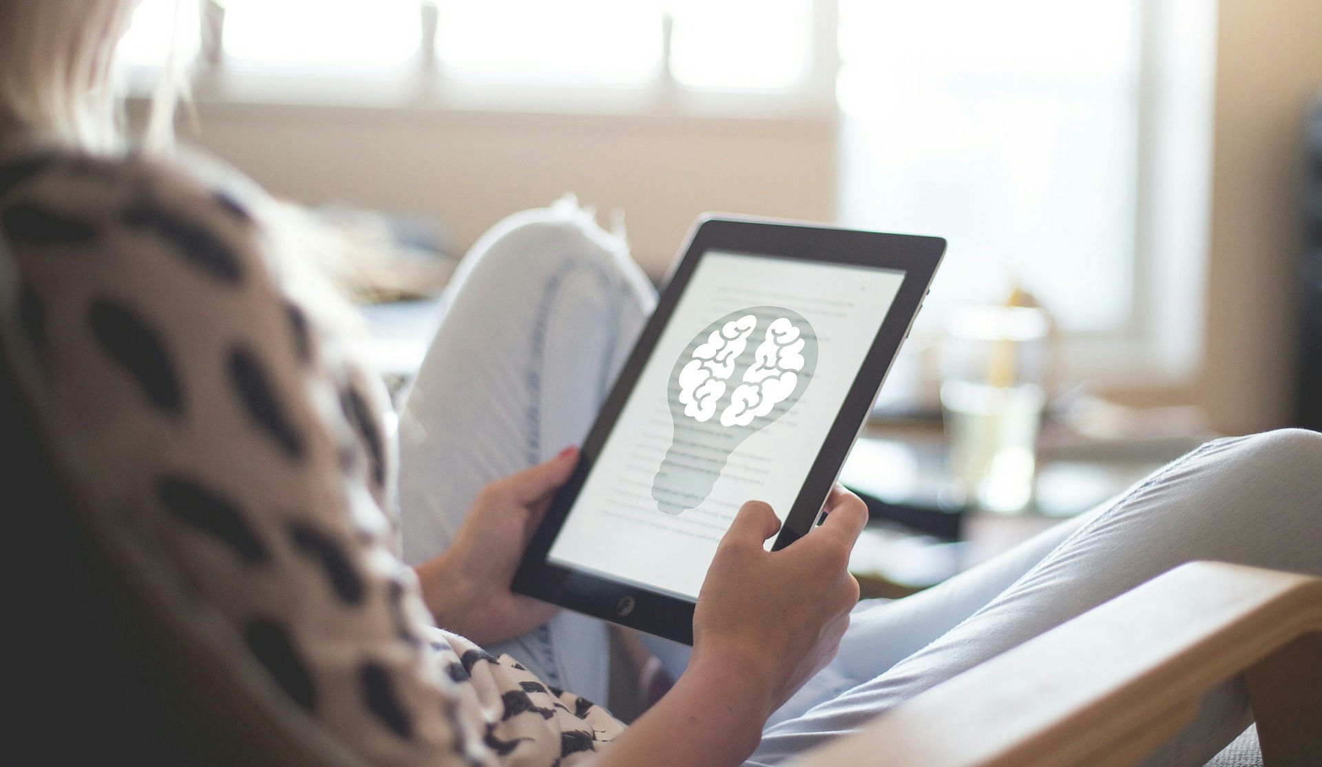 Person holding a tablet showing an illustrated light bulb.