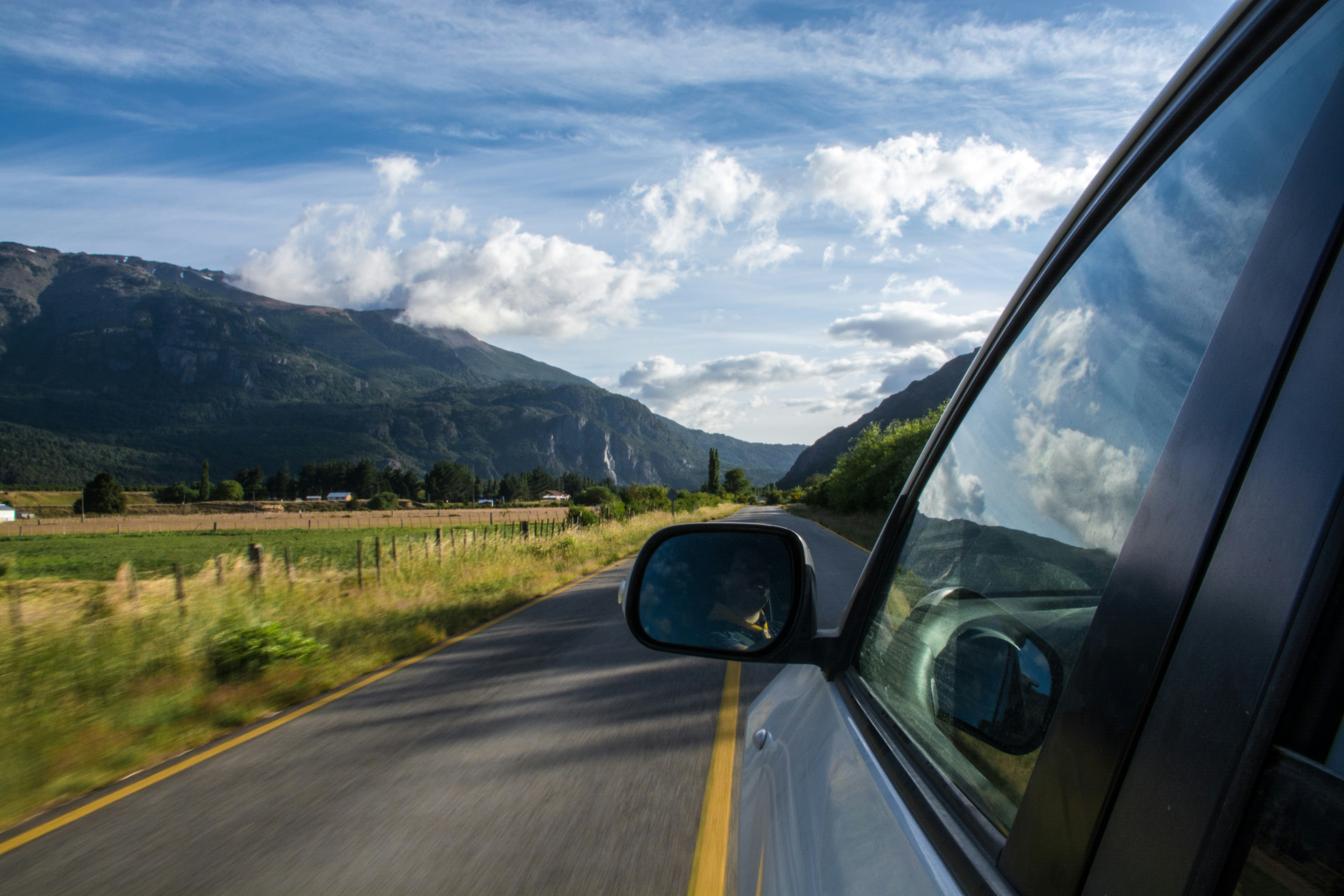 Photo of a car driving through a rural Scandinavian landscape