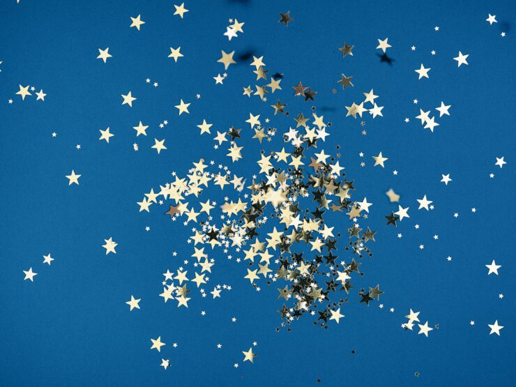 Gold star-shaped confetti on a blue background. Photo by Kier in Sight Archives on Unsplash